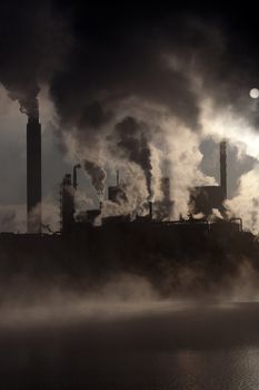 Paper mill covered by heavy smoke screen by hazy sunrise.