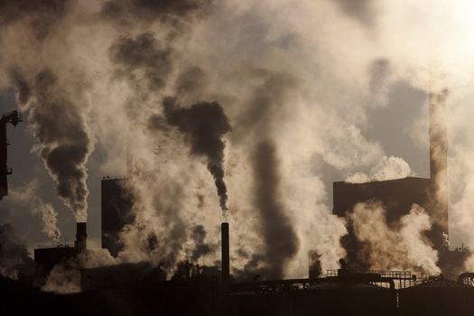 Paper mill covered by heavy smoke screen by hazy sunrise.