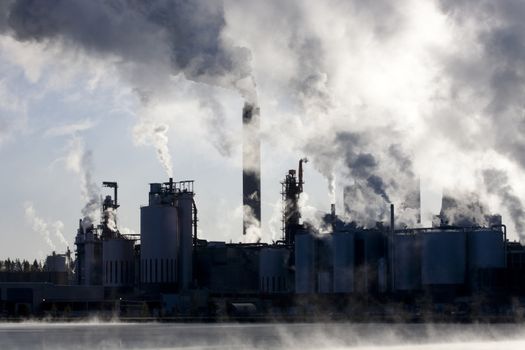 Paper mill covered by heavy smoke screen by hazy sunrise.