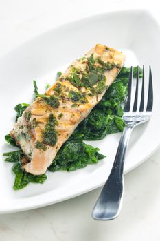 grilled salmon with herbs on fried spinach