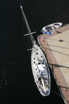Sailboat and motorboat moored to a pier on sunny summer day.