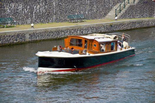 Passenger boat sails on the water channel along the stone quay.