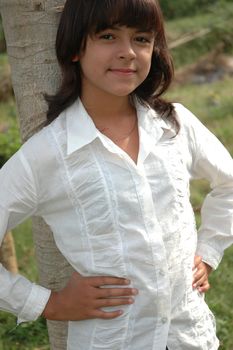 little asian girl stand up beside the tree in park