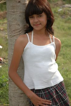 little asian girl stand up beside the tree in park