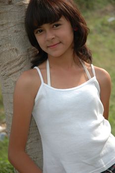 little asian girl stand up beside the tree in park