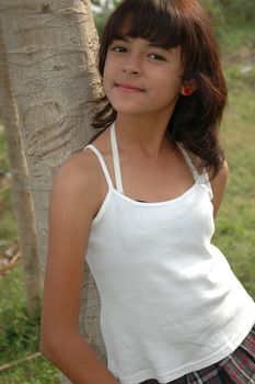 little asian girl stand up beside the tree in park