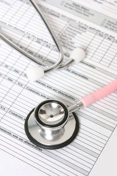 A nurses stethoscope sits on top of a patient records sheet.