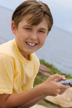 Child holding a portable game player and smiling to the viewer.