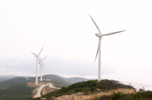 White electrical power generating wind turbines on rolling hills