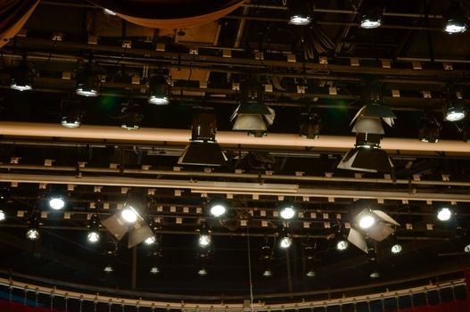 Multiple stage spotlight arrangement on ceiling of stage over black