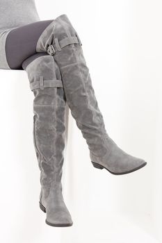 detail of sitting woman wearing fashionable gray boots