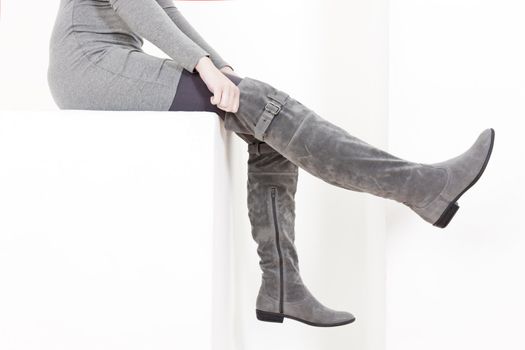 detail of sitting woman wearing fashionable gray boots