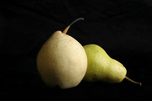 Two different variety of pears on a black background