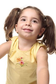 Beautiful radiant smiling toddler girl looking up.  She has pigtails and is wearing a yellow tank top with embroidery.