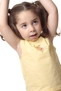 Closeup of a little girl with hands stretched above her head. She is wearing a yellow top with embroidery and has hair in ponytails.