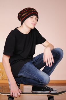 The teenager with a skateboard and in a hat isolated on white background