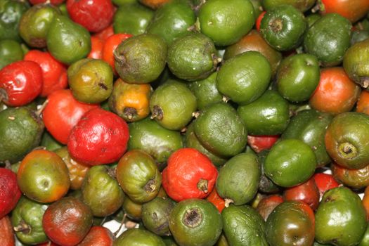 a pile of green and red locoto peppers on a vegetable market