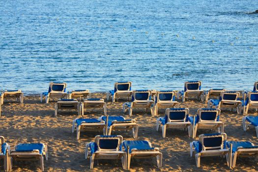 Group of blue beach chairs or beds on a sunset beach