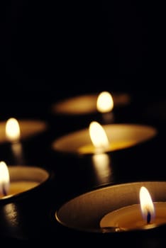 Vertical dark background with many lit candles