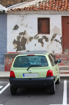 A small car parked in front of a vintage house