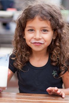 Cute little girl drinking a glass of milk