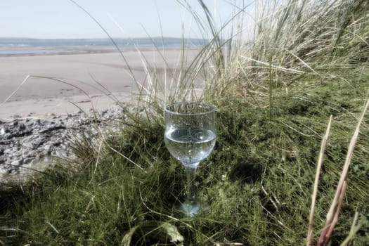 single glass of pure natural water standing on the beach dunes in kerry ireland