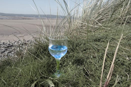 single glass of pure natural water standing on the beach dunes in kerry ireland