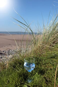 single glass of pure natural water standing on the beach dunes in kerry ireland