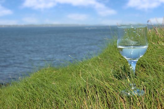 single glass of pure natural water standing on the beach dunes in kerry ireland
