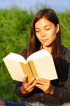 Woman student reading book in warm evening light.