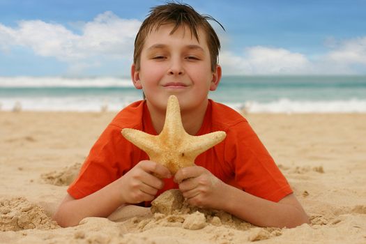 Child on sandy beach holds a starfish - focus on boy only.
1/500 @ f5