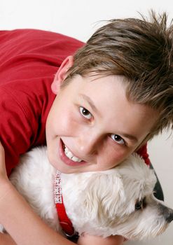 A boy cuddles a pet dog.