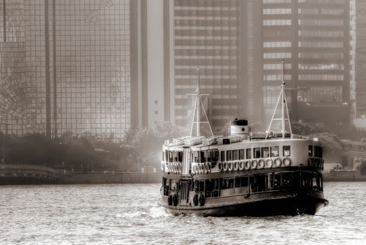 Boat on Victoria harbour in Hongkong with tall buildings.