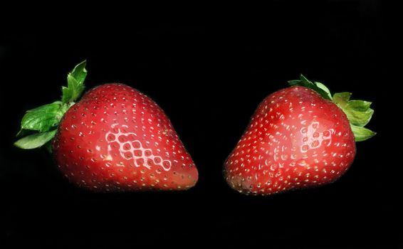 Two ripe juicy strawberries on black