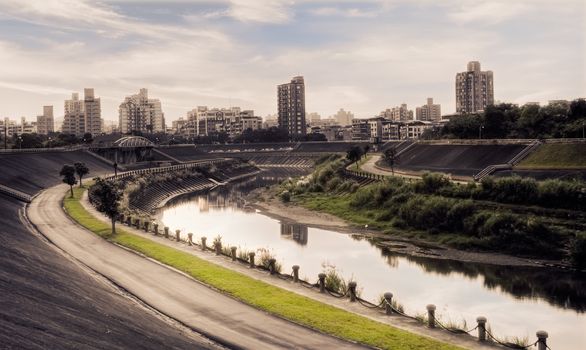 Cityscape of sunset with buildings and river in park in the evening.