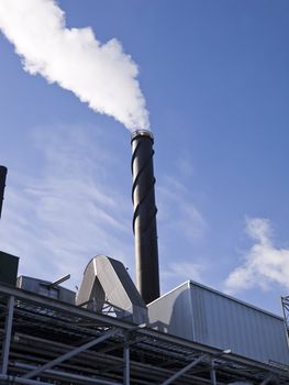 Chimney with smoke towards blue sky