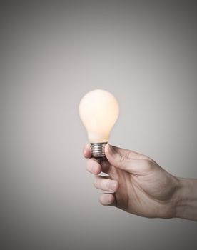 Hand holding shining light bulb
