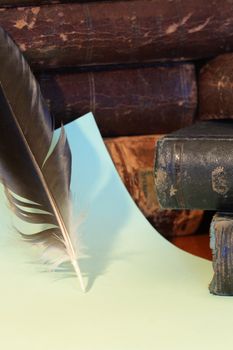 Closeup of feather on background with paper sheet and old books