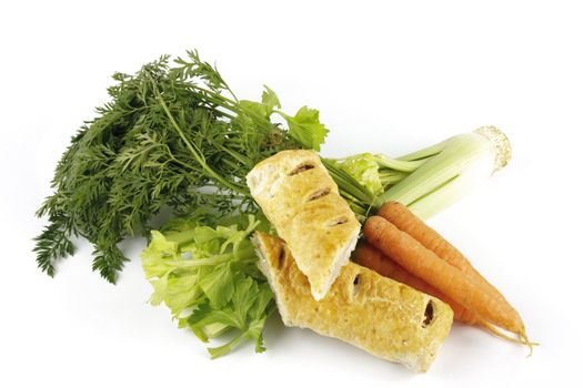 Contradiction between healthy food and junk food using a bunch of carrots and celery with a sausage roll on a reflective white background 