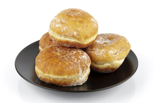 Black round plate of jam doughnuts on a reflective white background