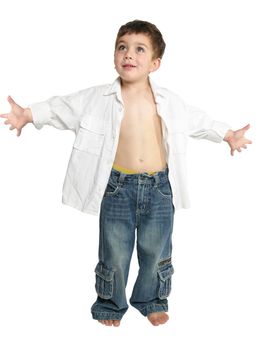 Toddler boy wearing blue jeans and white shirt stands with arms outstretched.