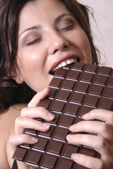 A beautiful woman with a large chocolate bar.  Satisfying a chocolate craving (
