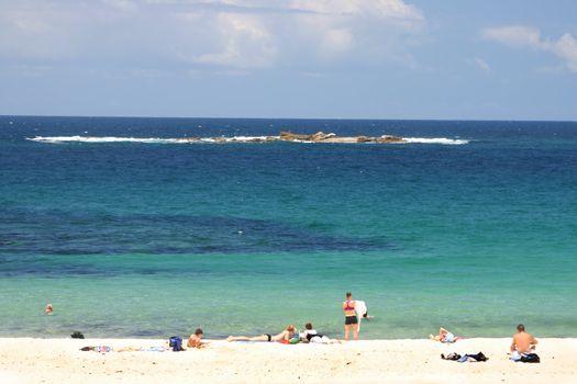 White sandy beach with sunbathers and swimmers Shot with added contrast and polarizer has an almost 3d effect.. Wedding Cake Is. in the distance.