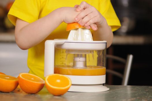 The child in a yellow vest to wring out juice  from an orange