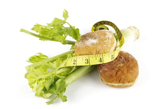 Contradiction between healthy food and junk food using celery and jam doughnut with a yellow tape measure on a reflective white background 