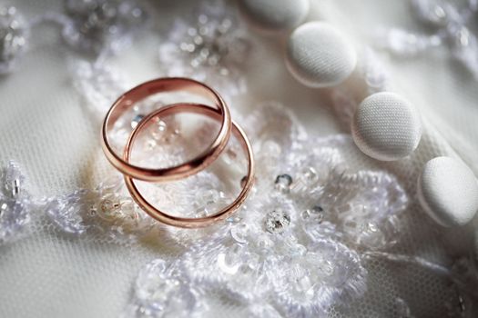Wedding rings on a background of a wedding dress. 