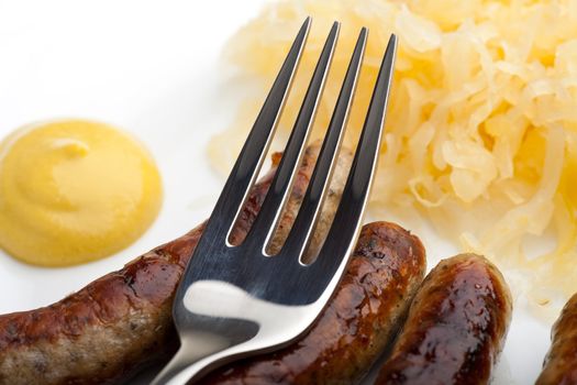 fried sausages,mustard and sauerkraut on a plate with a fork