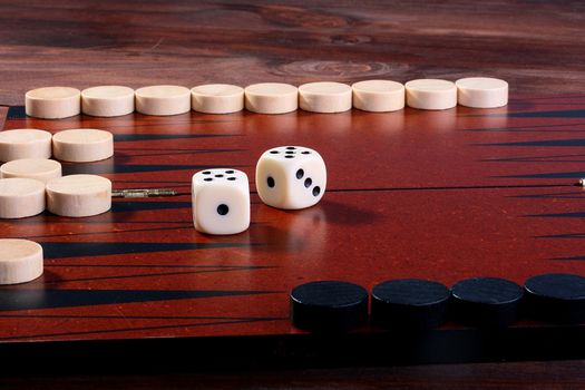 Backgammon, in the foreground in focus black counters, on a background of a counter of the contender and cubes.