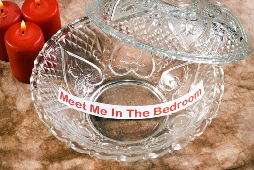 An erotic memo left inside a glass candy dish with some red candles bruning beside it