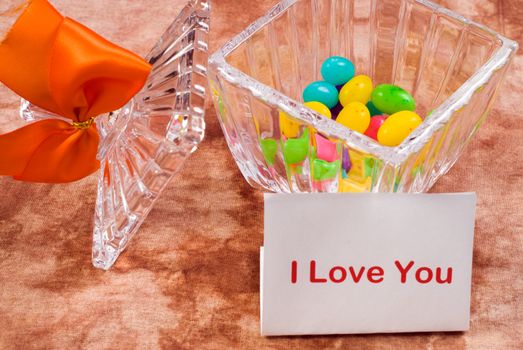 A love note sitting beside a candy dish with a bow on it